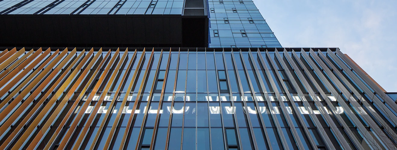 Modern glass building facade with orange vertical louvers and reflective windows, a contemporary architectural detail.